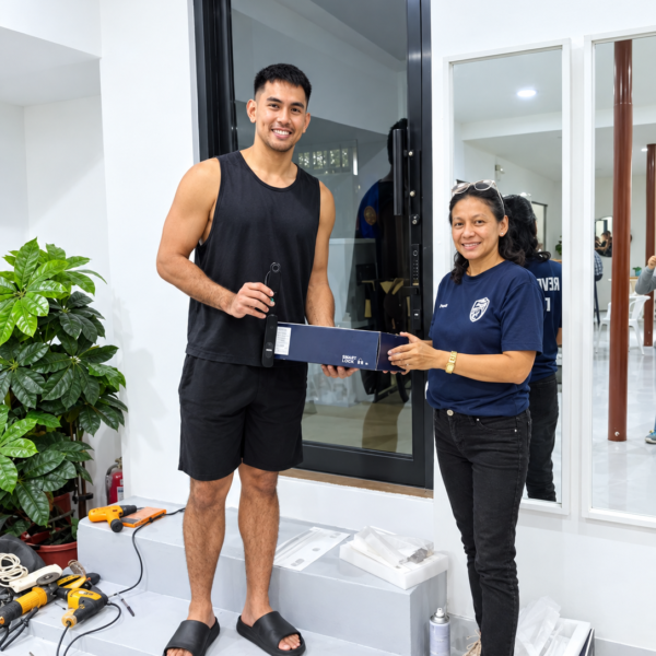 Two people holding a smart lock and its box beside a glass entrance door
